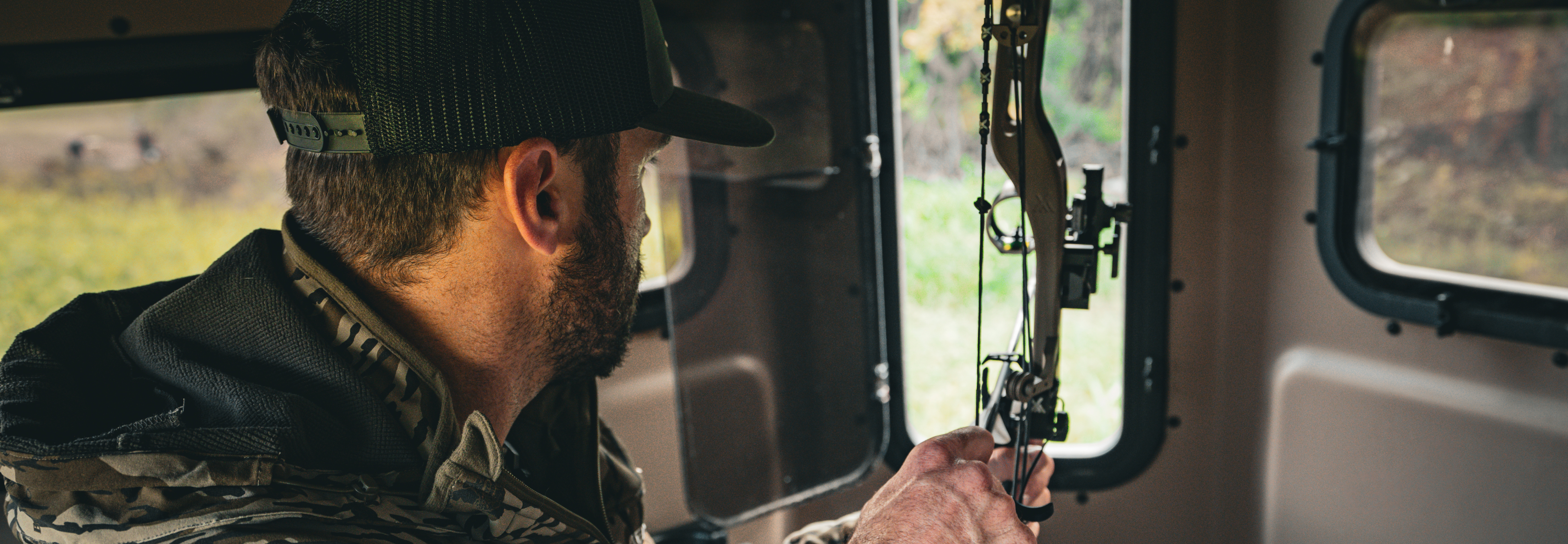 Man in camouflage gear using a bow inside a Titan Hunting Blind